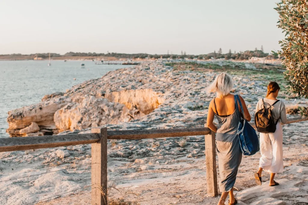 Two women casually hiking on a beach trail by the ocean