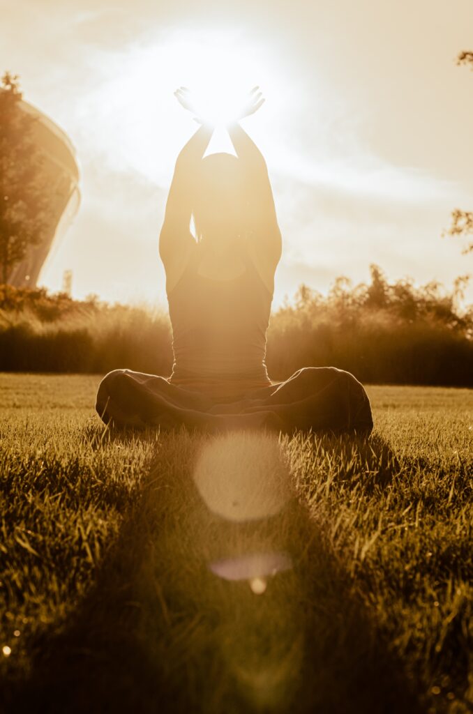 Woman sitting in meditation with the sun setting