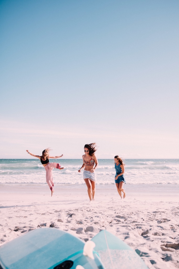 Group of women running and being playful on the beach in San Diego.