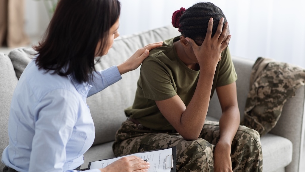 Female Psychologist Comforting Soldier Woman During Therapy Session In Office