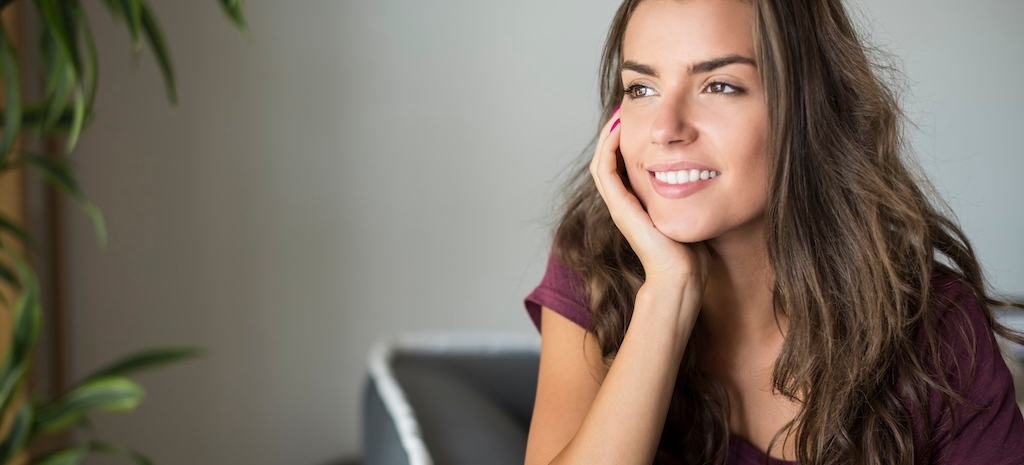 Young woman looking out the window, feeling hopeful