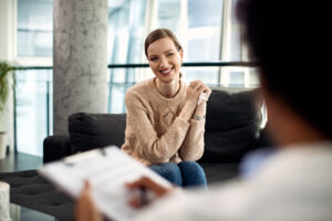 Young happy woman communicating with psychologist during therapeutic session.