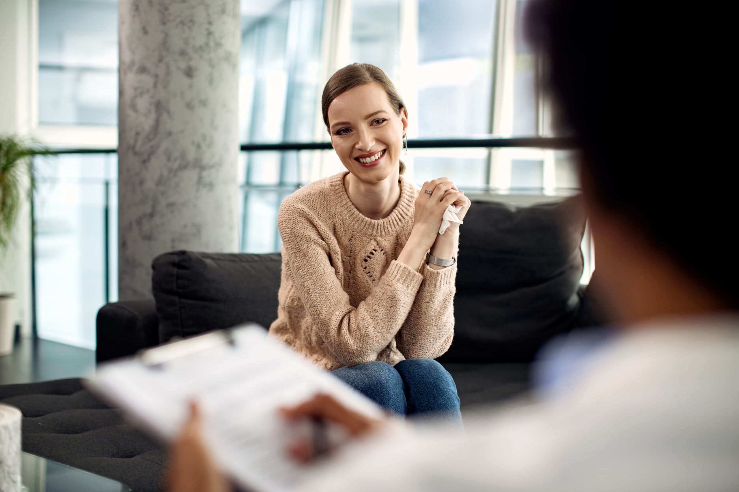 Young happy woman communicating with psychologist during therapeutic session.