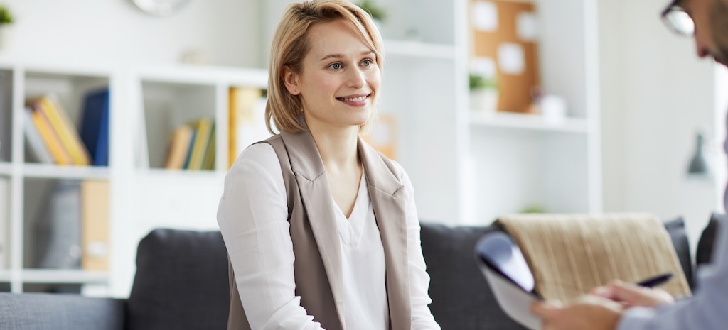 Happy young casual woman looking at her counselor while listening to his advice during individual session