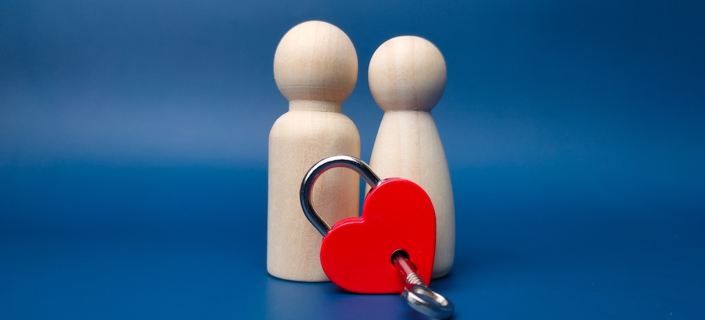 Attachment concept with two wood figures and a heart with a key