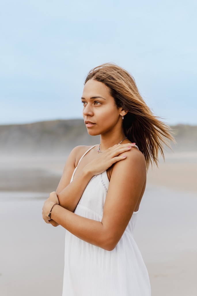 portrait of young woman on the beach looking into the distance.