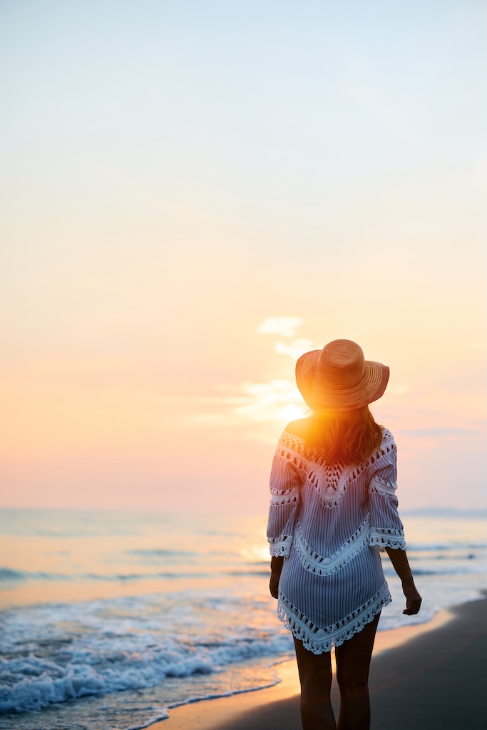 Rear view of woman enjoying in sunset on the beach.