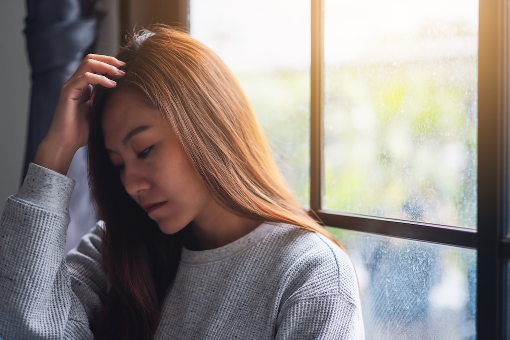 A sad and stressed young woman sitting alone in the room