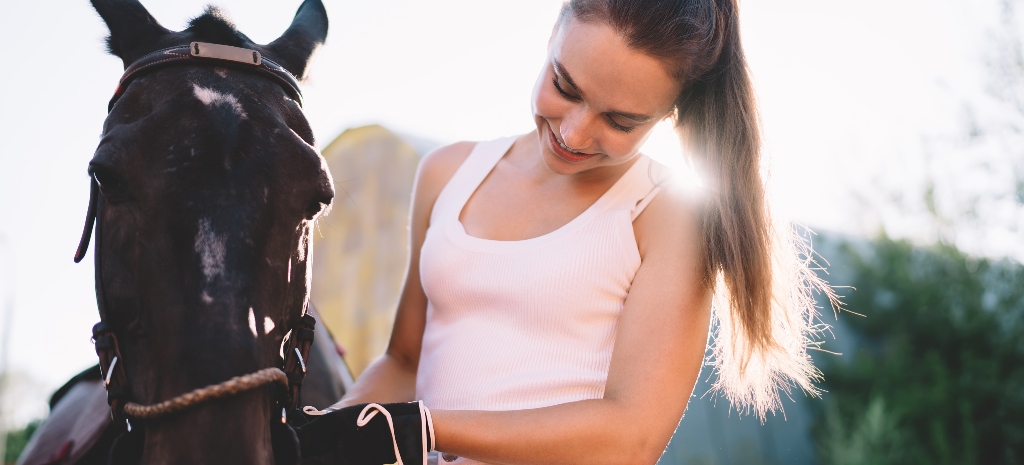 Young woman smiling down at horse during equine for mental health therapy session