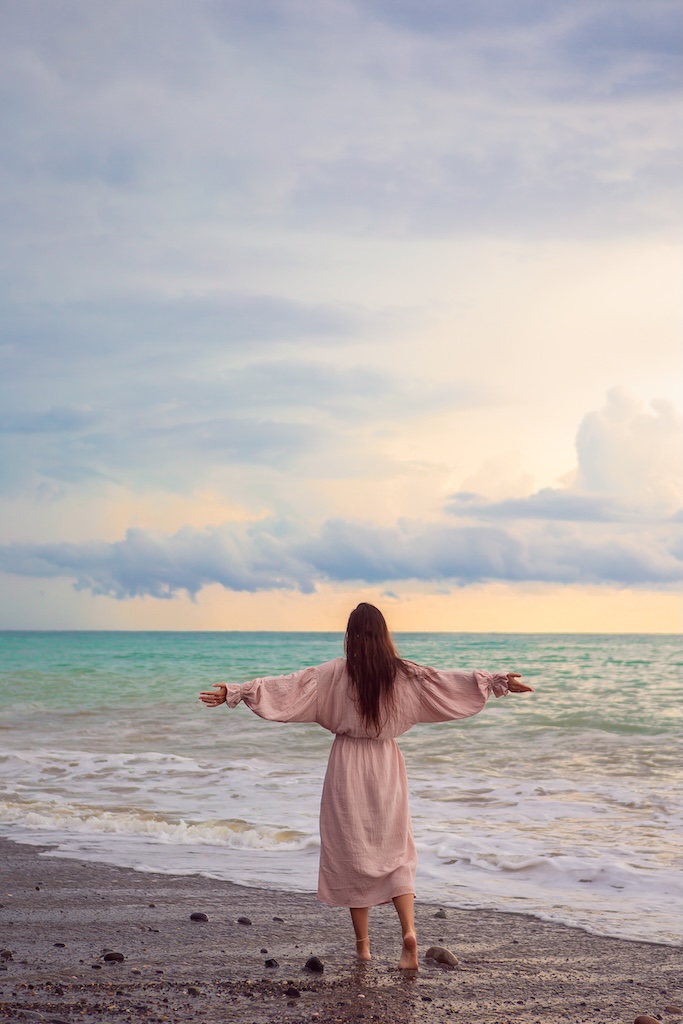 woman feeling freedom on the beach at sunset