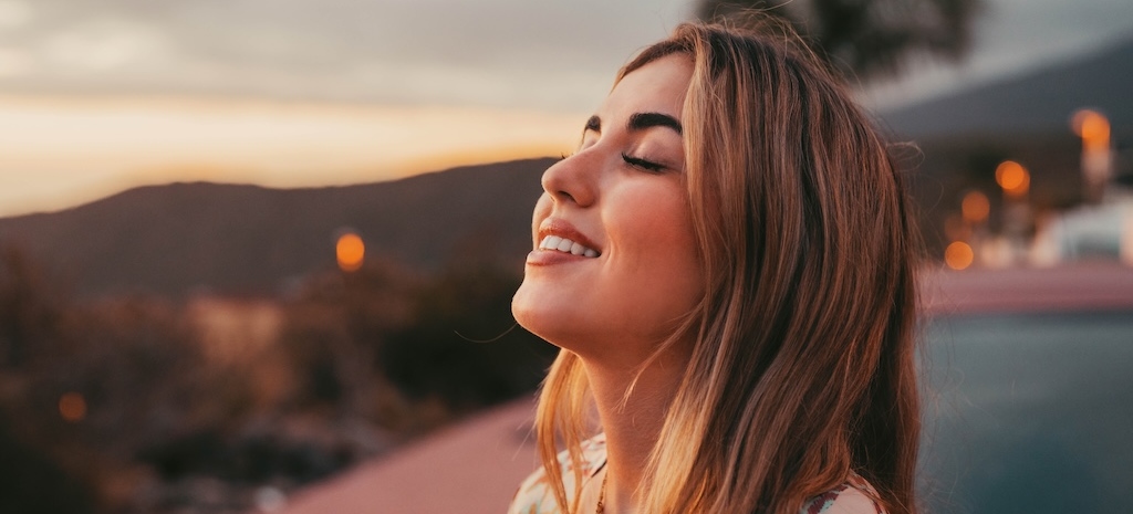 Portrait close up of face of one young beautiful woman smiling with closed eyes enjoying freedom emotion