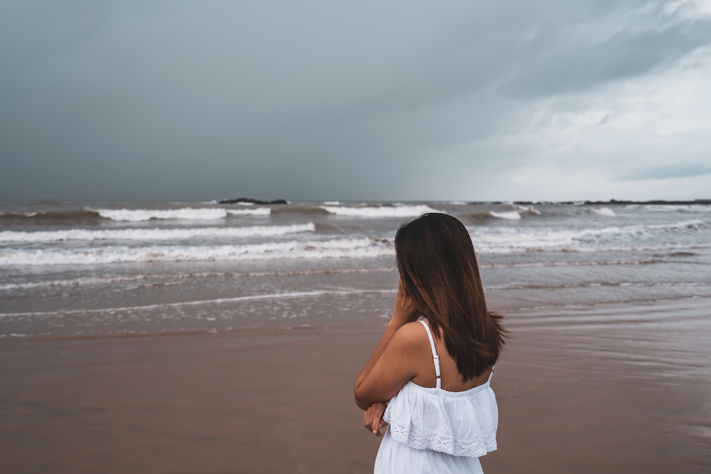 Young woman feeling lonely and sad looking at the sea on a gloomy day