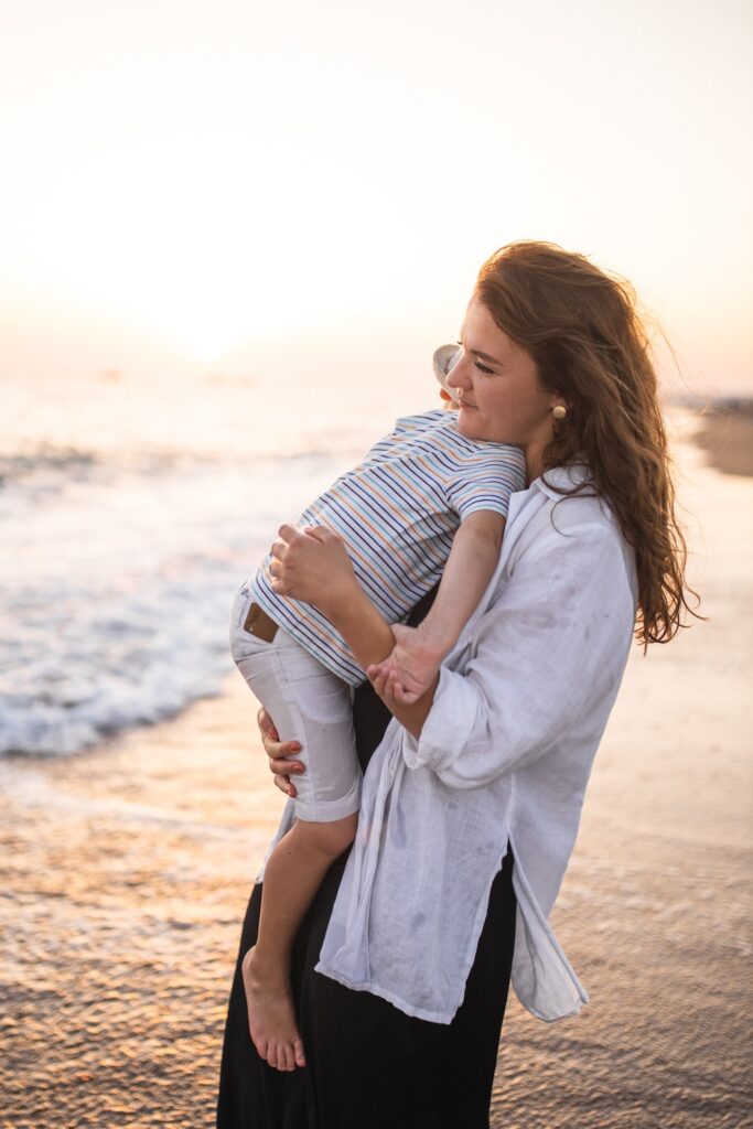 Young mother holding her son on the beach, representing healing and rediscovering the joy of motherhood