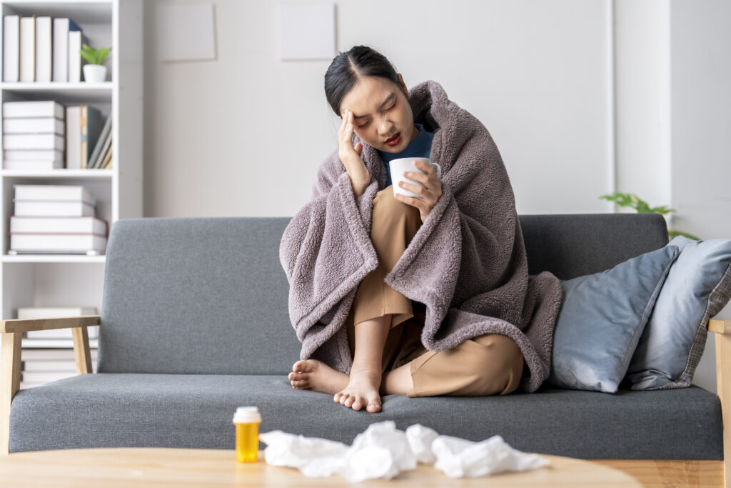 A woman is sitting on a couch with a blanket wrapped around her