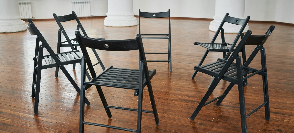 Group of chairs seated in a circle in a room with wood floors. 