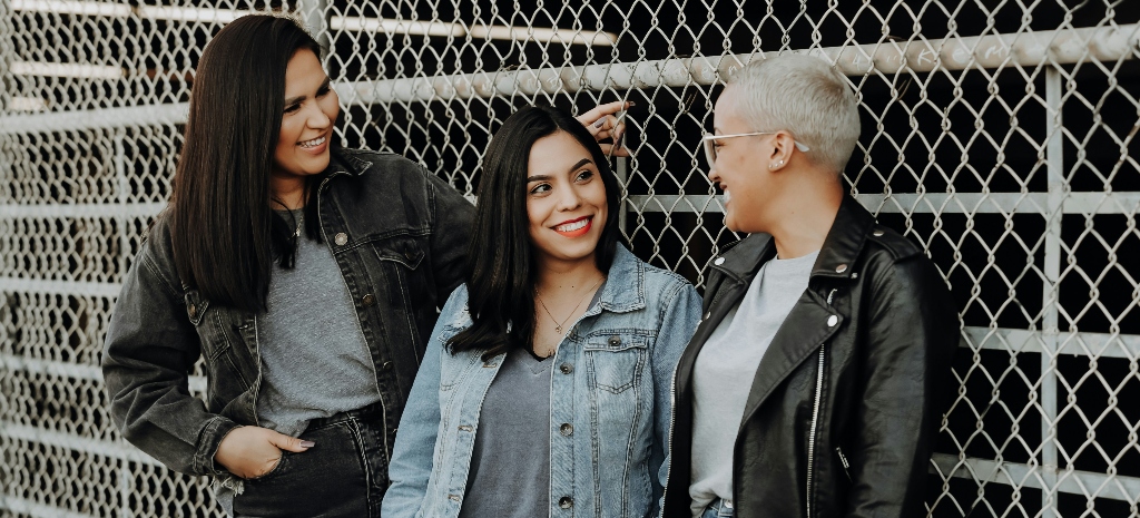 Three women smiling and connecting with each other outdoors, illustrating the role of safe relational connection and co-regulation in nervous system healing and recovery.