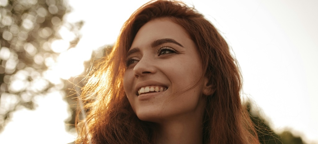 Woman smiling in sunlight, representing hope and healing—get support for alcohol use or binge drinking at Monima Wellness.