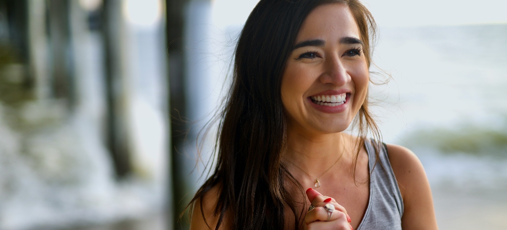 Smiling woman outdoors near the beach representing emotional healing, connection, and mental wellness support.