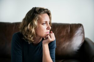 Woman sitting by a window in quiet reflection, representing the emotional effects of complex trauma and CPTSD.