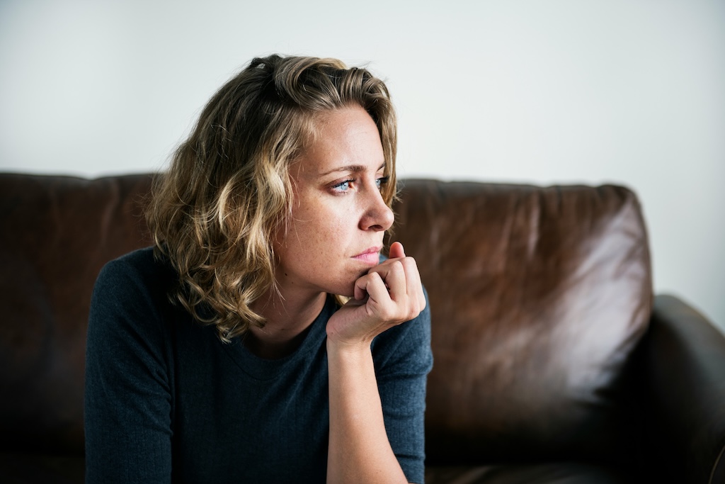 Woman sitting by a window in quiet reflection, representing the emotional effects of complex trauma and CPTSD.