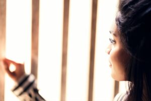 Woman looking out a window in soft light.