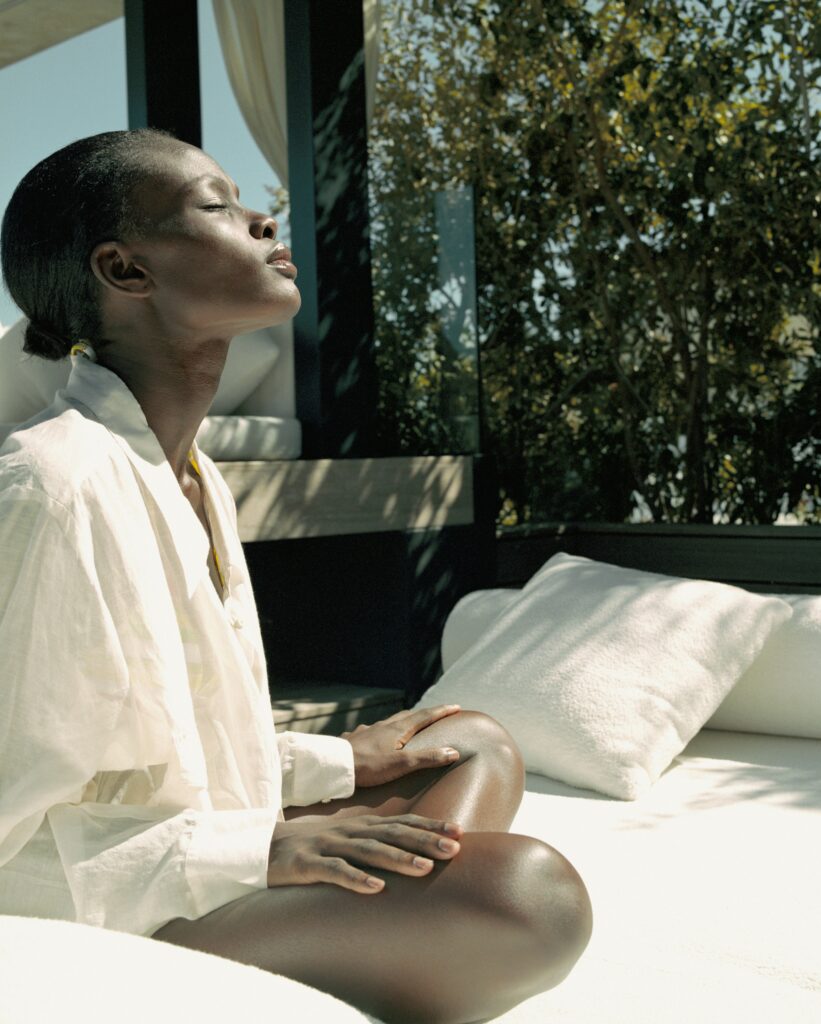 Woman sitting peacefully in sunlight near a window.