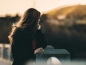 Woman standing outdoors and looking thoughtfully toward the sunset.