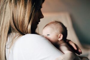 Mother holding her newborn baby close during the postpartum period.