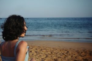 Woman sitting alone on a beach looking out at the ocean, representing the internalized emotions associated with quiet BPD.