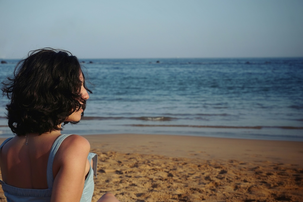 Woman sitting alone on a beach looking out at the ocean, representing the internalized emotions associated with quiet BPD.
