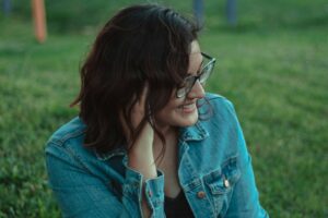 Woman with glasses sitting outdoors, illustrating autism in women.
