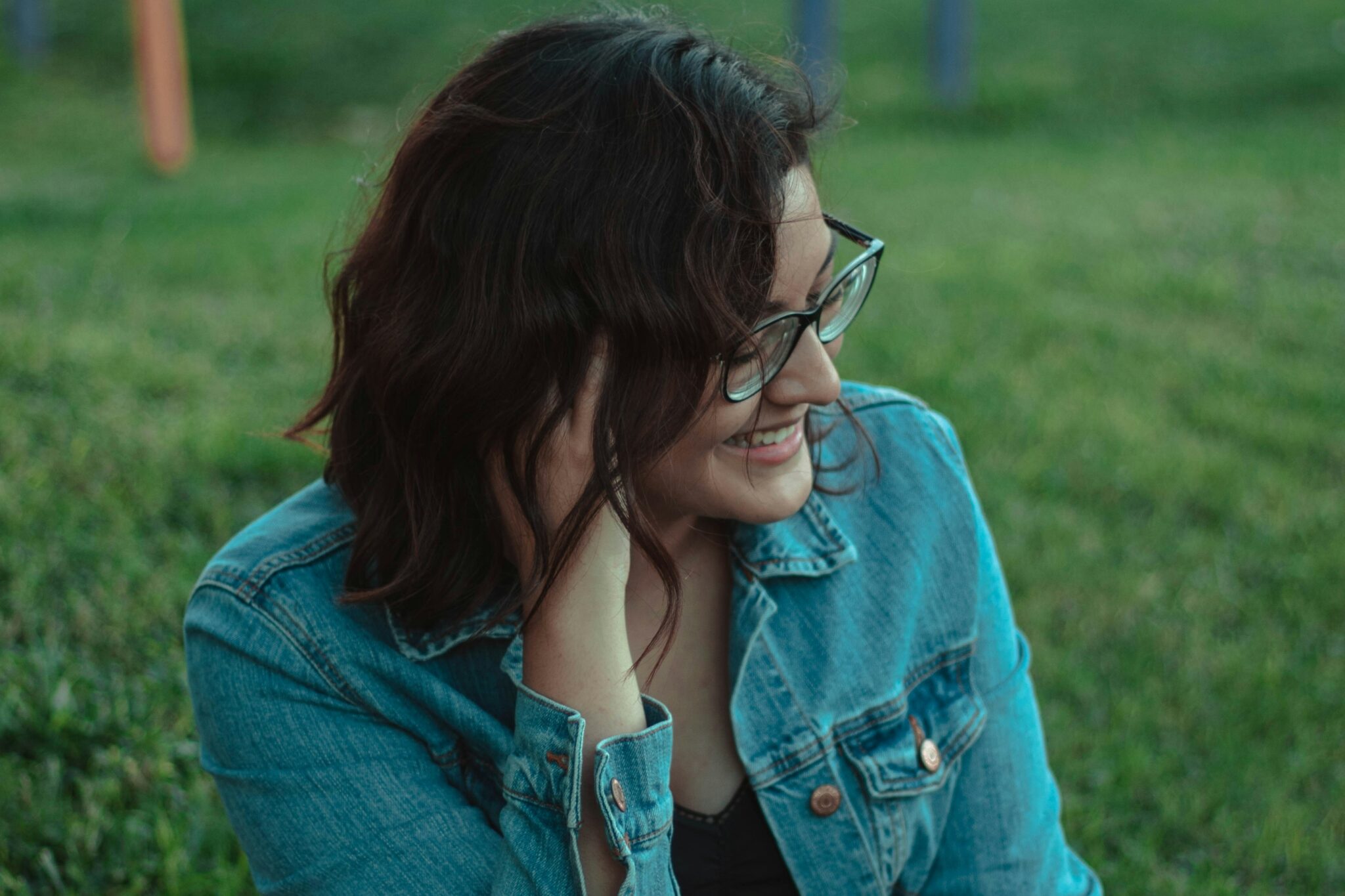 Woman with glasses sitting outdoors, illustrating autism in women.