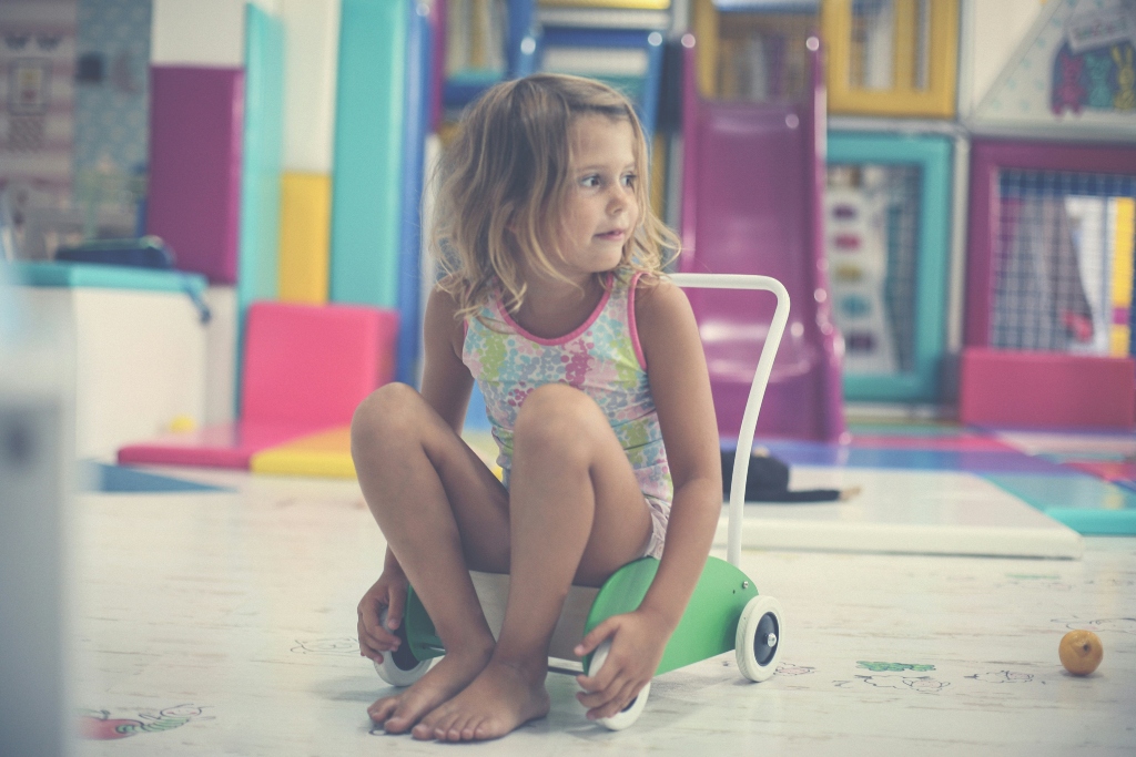 Young girl sitting alone in a colorful playroom, illustrating childhood emotional neglect.